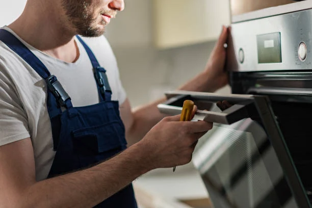 Technician reviewing a tablet while inspecting a stainless steel oven